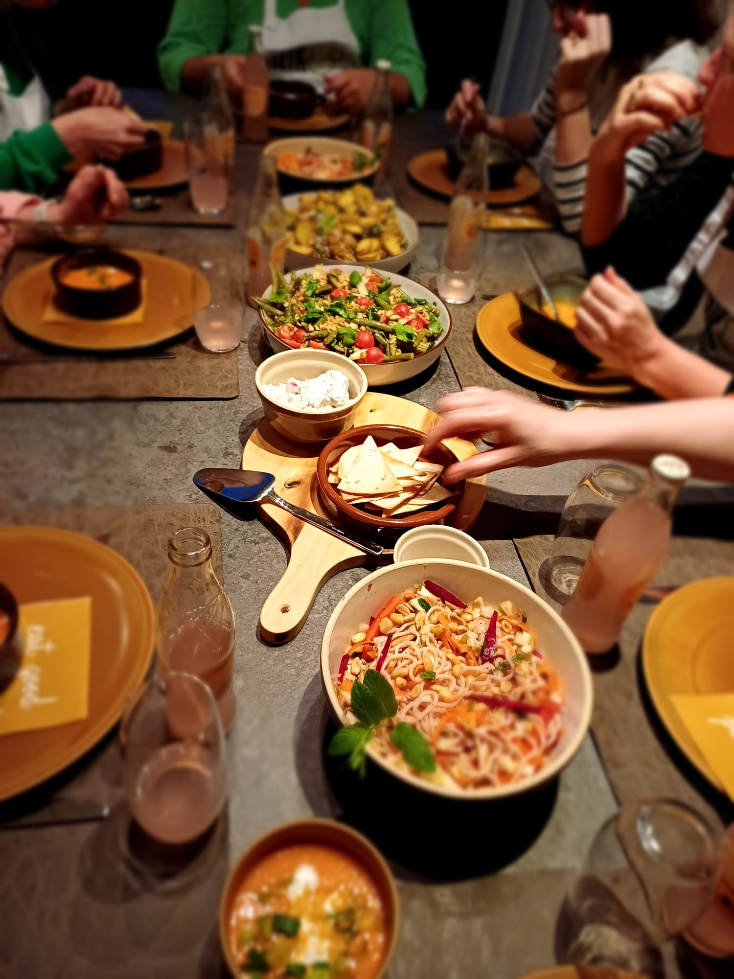 Gedekte tafel vol veggie gerechten met mensen rond de tafel